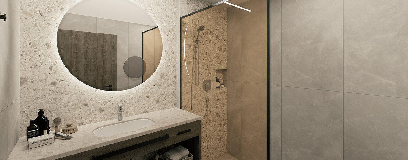 Modernes Badezimmer mit einem großen runden Spiegel über einem Waschbecken mit Steinplatte, einem hölzernen Waschtisch mit Handtüchern und Körben darunter und einer glasumschlossenen begehbaren Dusche mit Steinwänden und einer eingebauten Nische für Duschartikel..