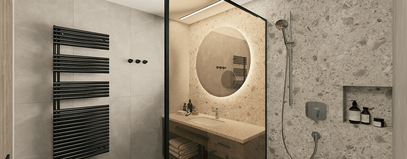Modernes Badezimmer mit einem runden, beleuchteten Spiegel über dem Waschbecken, einem offenen Regal mit Handtüchern darunter, einem schwarzen Handtuchheizkörper, einer Dusche mit Steinstruktur und eingebauten Ablagen sowie einer Glastrennwand zur Abtrennung des Duschbereichs.