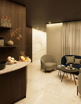 Eine gemütliche Wellness Lounge mit einem geschwungenen Sofa, zwei Sesseln, einem runden Couchtisch und Pendelleuchten. Regale mit Gläsern und Dekoration, eine Arbeitsplatte mit Obst und helle Vorhänge vervollständigen den warmen, einladenden Raum.