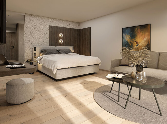 Modernes Schlafzimmer mit einem großen Bett, neutralen Tönen, einem grauen Sofa, runden Couchtischen, einer kleinen Ottomane und abstrakter Wandkunst. Helle Holzböden und sanftes natürliches Licht schaffen eine gemütliche Atmosphäre.