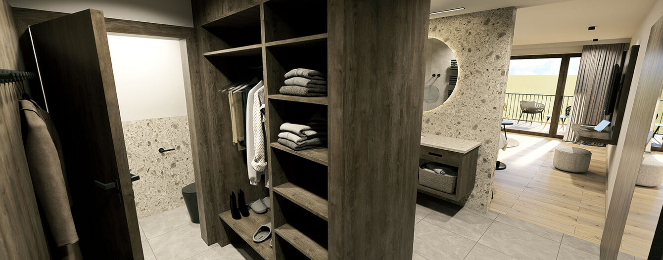 Moderner begehbarer Kleiderschrank mit dunklen Holzregalen, hängenden Kleidungsstücken und gefalteten Gegenständen. Angrenzendes Badezimmer mit großem runden Spiegel; Schlafzimmer mit großen Fenstern und Balkon ist im Hintergrund zu sehen. Helle Fliesenböden überall.